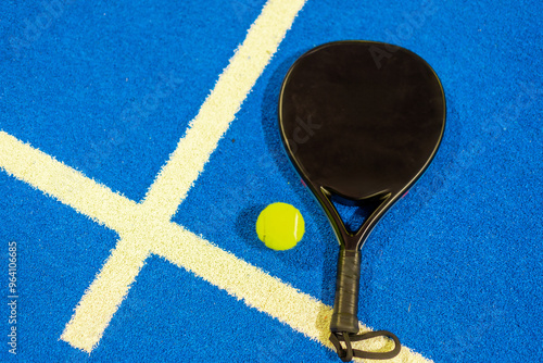 Paddle tennis racket and ball in a blue court photo