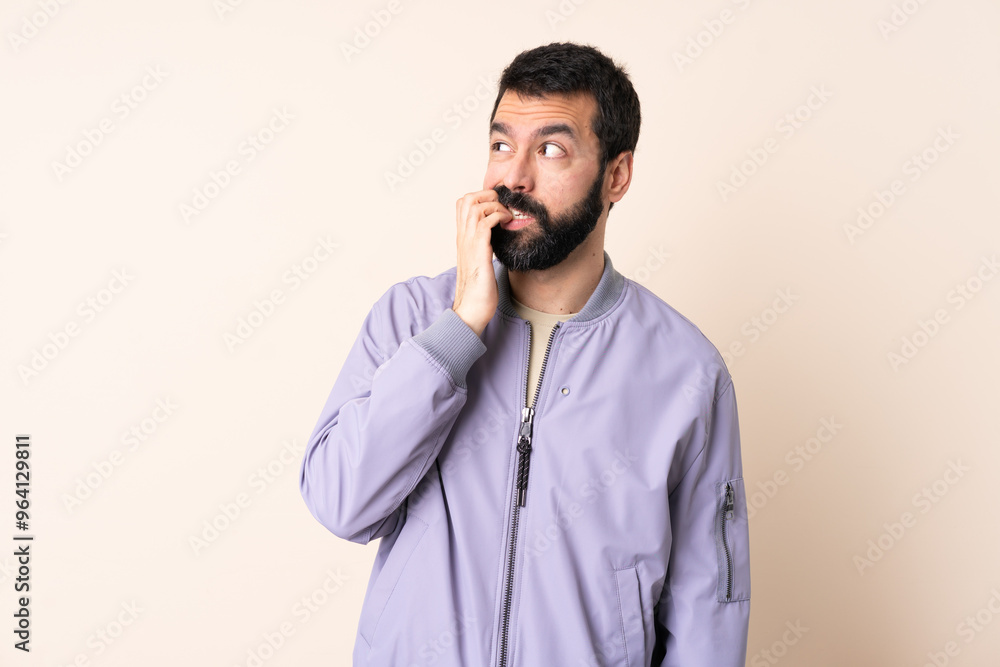 Caucasian man with beard wearing a jacket over isolated background is a little bit nervous Caucasian man with beard wearing a jacket over isolated background is a little bit nervous
