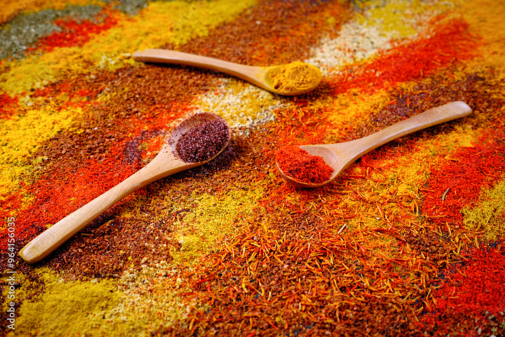 Close-up of many different colorful natural spices and wooden spoons. Close-up of many different colorful natural spices and wooden spoons.