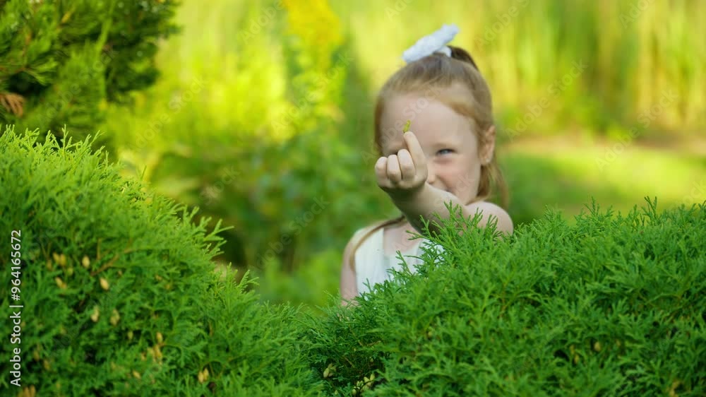 Portrait of little girl having fun in summer garden. Child dressed in lovely white dress. Girl relaxing outdoors. Sunlight creating magical atmosphere as she interacts with beauty surrounding her.