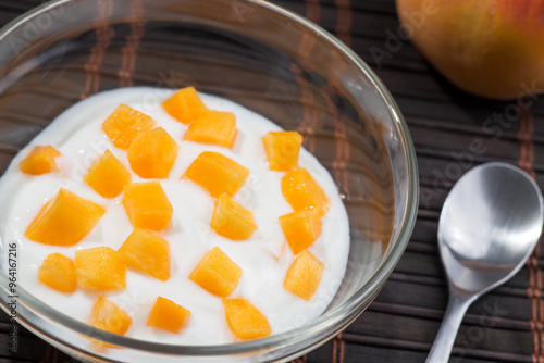 Natural lactose-free yogurt dessert with peach pieces in a glass bowl.