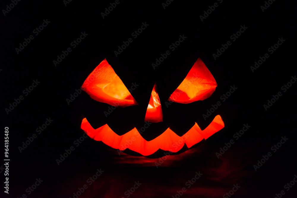 Carved halloween pumpkin jack-o-lantern glows in a darkness Carved halloween pumpkin jack-o-lantern glows in a darkness