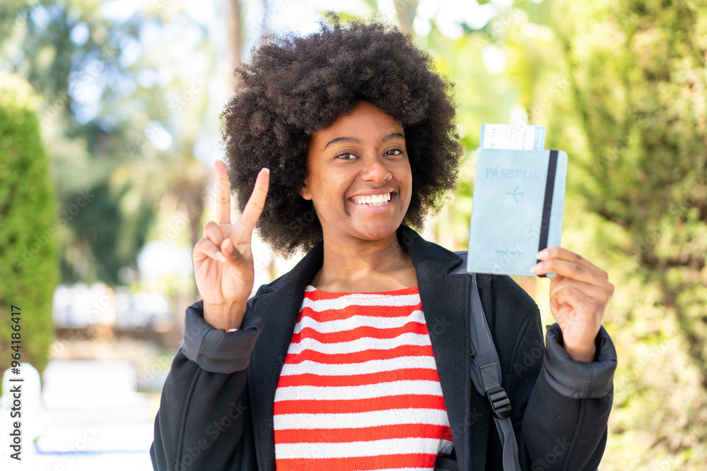 African American girl holding a passport at outdoors smiling and showing victory sign African American girl holding a passport at outdoors smiling and showing victory sign