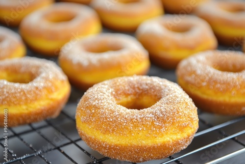 A batch of baked pumpkin donuts dusted with cinnamon sugar, arranged on a cooling rack