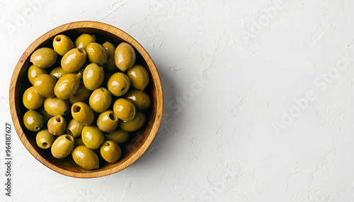 Wooden bowl with green olives on white background photo