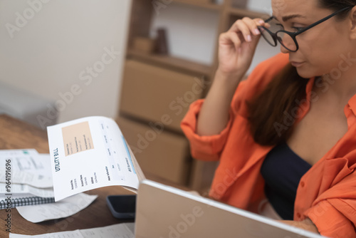  woman, at home, distressed by a utility bill, contemplates mortgage payment challenges and escalating debt. photo