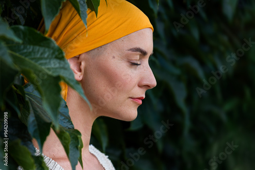 Bild auf Leinwand Young female cancer patient wearing headscarf closed eyes side view garden portrait