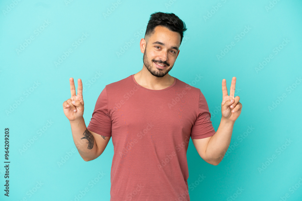 Young caucasian man isolated on blue background showing victory sign with both hands Young caucasian man isolated on blue background showing victory sign with both hands