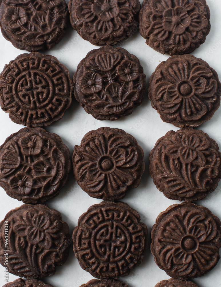Overhead view of stamped chocolate cookies on a parchment lined baking tray, top view of embossed chocolate sugar cookies on a white background Overhead view of stamped chocolate cookies on a parchment lined baking tray, top view of embossed chocolate sugar cookies on a white background