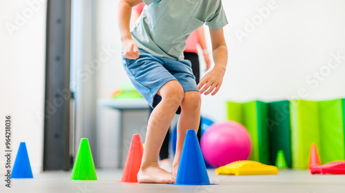 Young boy exercising with female physical therapist during therapy session. Child occupational physical therapy. Bilateral coordination. photo