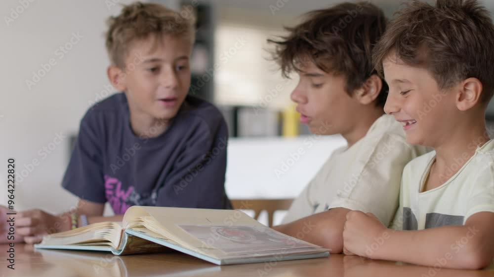 Three young boys gather around a table, laughing and sharing stories as they flip through the pages of a family photobook, creating cherished memories together, in slow motion. Three young boys gather around a table, laughing and sharing stories as they flip through the pages of a family photobook, creating cherished memories together, in slow motion.