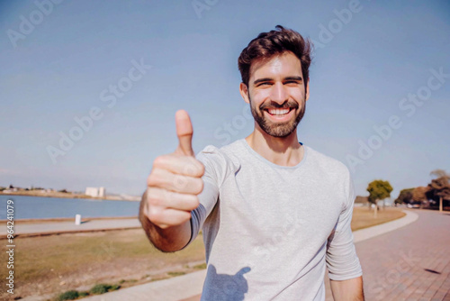 Man Giving Thumbs Up Near Water with White Building in Background photo