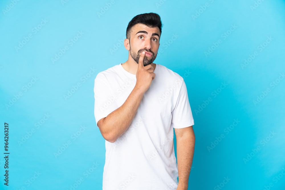 Caucasian man over isolated blue background having doubts while looking up Caucasian man over isolated blue background having doubts while looking up