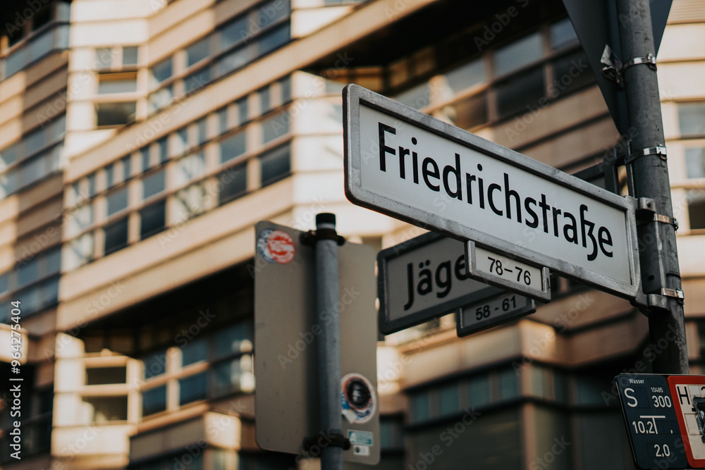 Close-up of the Friedrichstraße street sign in Berlin with modern buildings in the background. A famous street in the heart of Berlin, blending history, culture, and urban architecture. Close-up of the Friedrichstraße street sign in Berlin with modern buildings in the background. A famous street in the heart of Berlin, blending history, culture, and urban architecture.