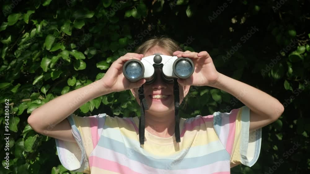 Smiling kid girl with binoculars on green nature background. Happy child scout outdoors. Concept of summer camp, adventure, scouting and tourism for children Smiling kid girl with binoculars on green nature background. Happy child scout outdoors. Concept of summer camp, adventure, scouting and tourism for children