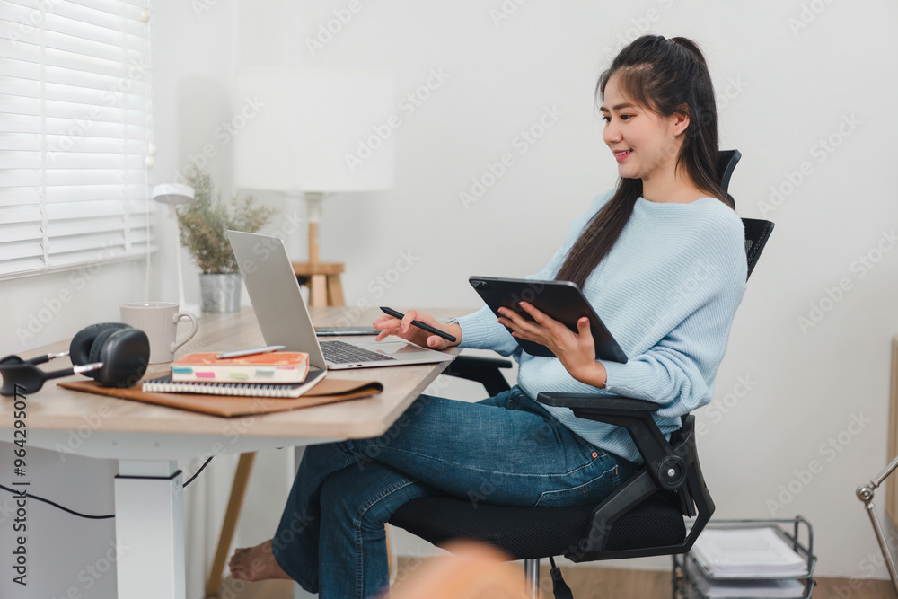 Asian woman working on digital tablet at desk. Asian woman working on digital tablet at desk.