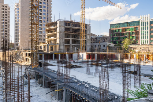 Construction site covered with snow. Erection buildings in winter. Construction site with reinforcement for pouring supports. Erection tall monolithic buildings. Construction background with blue sky