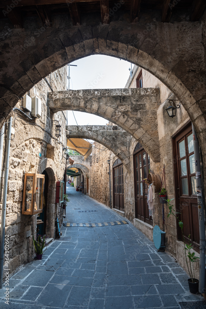 Narrow alley (Pythagoras street) with stone arches in the medieval town quarter of Rhodes, Greece. Narrow alley (Pythagoras street) with stone arches in the medieval town quarter of Rhodes, Greece.