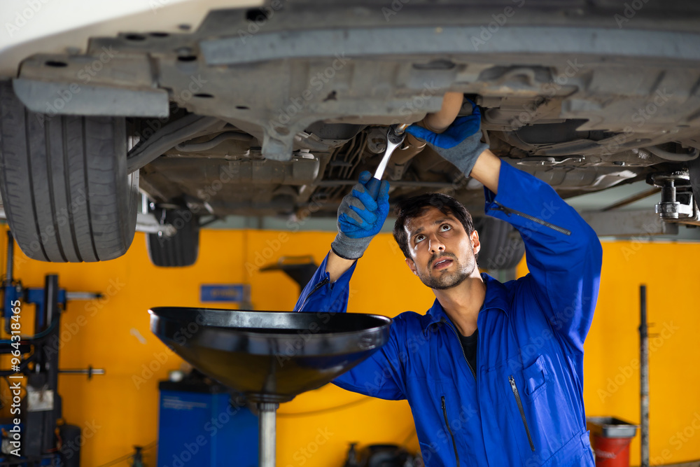 Chang car oil. Portrait hispanic latin male mechanic repairs car in garage. Car repair maintenance and auto service garage concept Chang car oil. Portrait hispanic latin male mechanic repairs car in garage. Car repair maintenance and auto service garage concept