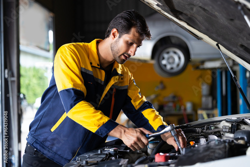 Close up mechanical hand with tools and spanner. Hispanic latin male mechanic repairs car in garage. Car maintenance and auto service garage concept