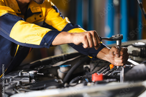 Close up mechanical hand with tools and spanner. Hispanic latin male mechanic repairs car in garage. Car maintenance and auto service garage concept