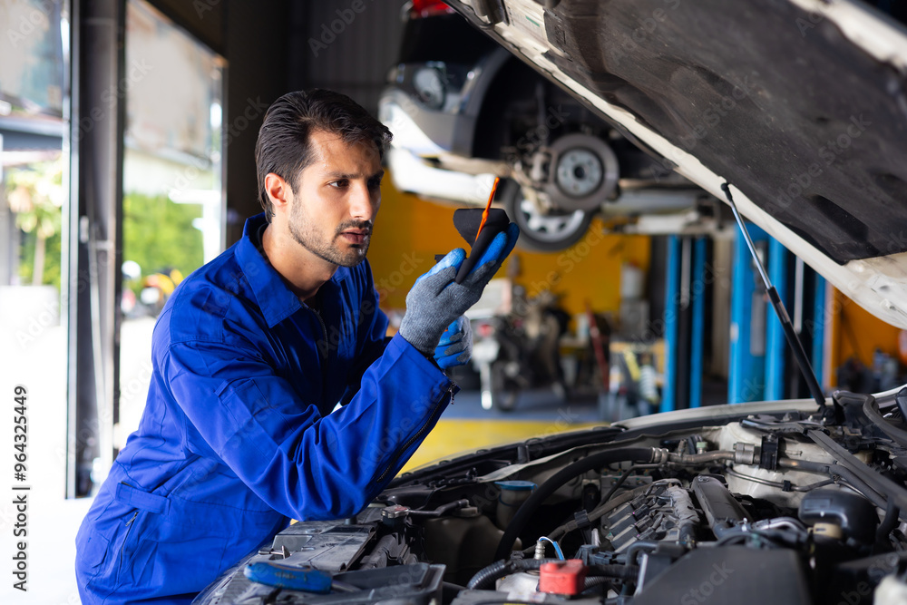 hispanic latin male mechanic repairs car in garage. Closeup hand. Auto car mechanic checking the oil level of the car engine. Car repair and maintenance hispanic latin male mechanic repairs car in garage. Closeup hand. Auto car mechanic checking the oil level of the car engine. Car repair and maintenance