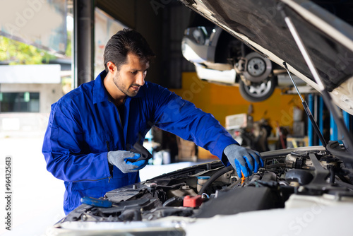 hispanic latin male mechanic repairs car in garage. Closeup hand. Auto car mechanic checking the oil level of the car engine. Car repair and maintenance