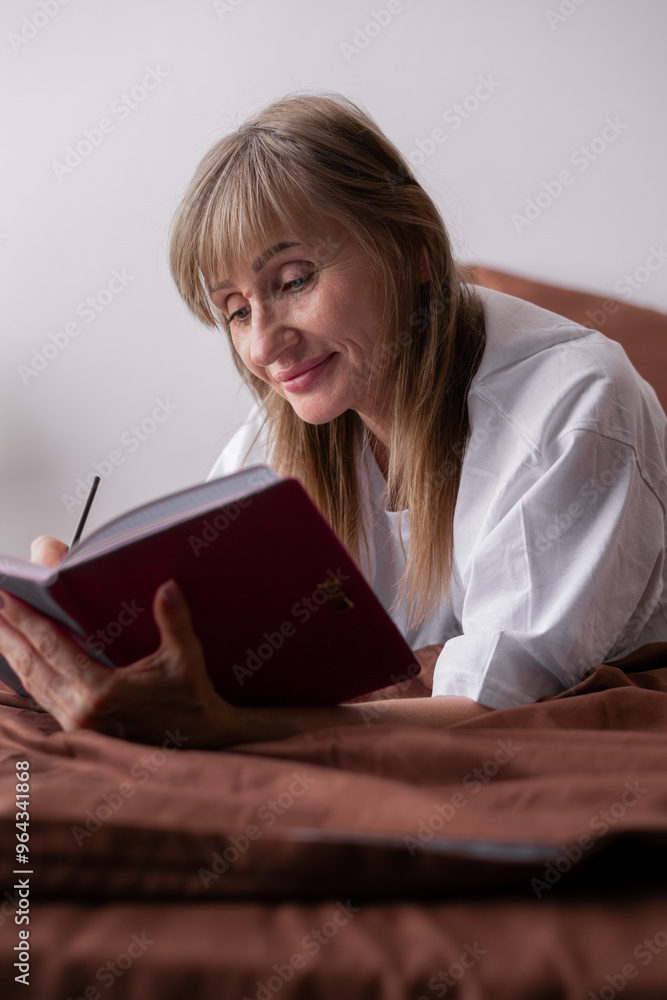 Senior woman writing in journal laying in the bed in the morning. Senior woman writing in journal laying in the bed in the morning.