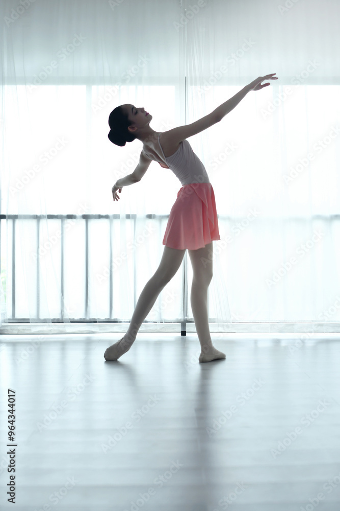 Fototapeta premium Teenage ballerina practices ballet in a pink outfit in a studio