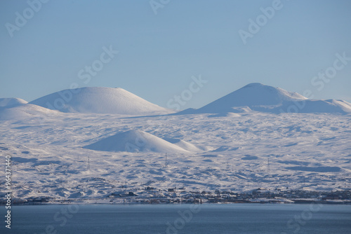 snow capped mountains on lake sevan in clear weather at sunset