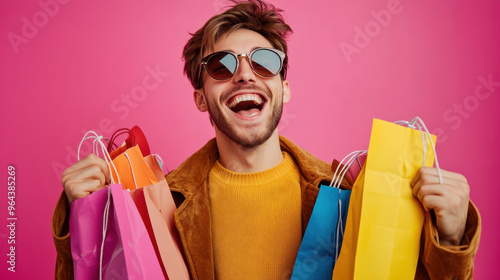 Happy man with shopping bags in colorful background. Excited about purchases. Smiling while holding multiple bags in vibrant colors.