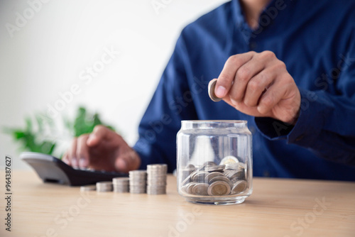 Man saving money concept. hand holding coins putting in jug glass , Planning step up, saving money for future plan, retirement fund , Concept business finance saving money and investment.