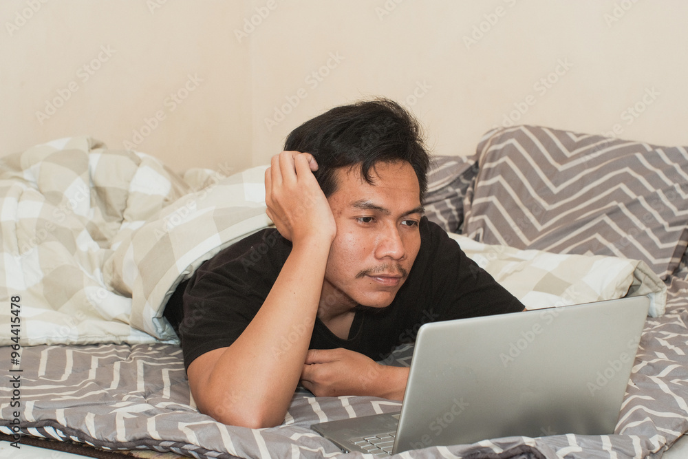 A Southeast Asian man watching movie in bed. Handsome man enjoying free time at home A Southeast Asian man watching movie in bed. Handsome man enjoying free time at home