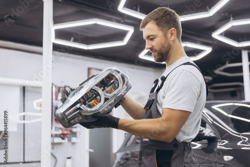 Mechanic in Modern Workshop Inspecting Car Headlight with Precision and Focus photo