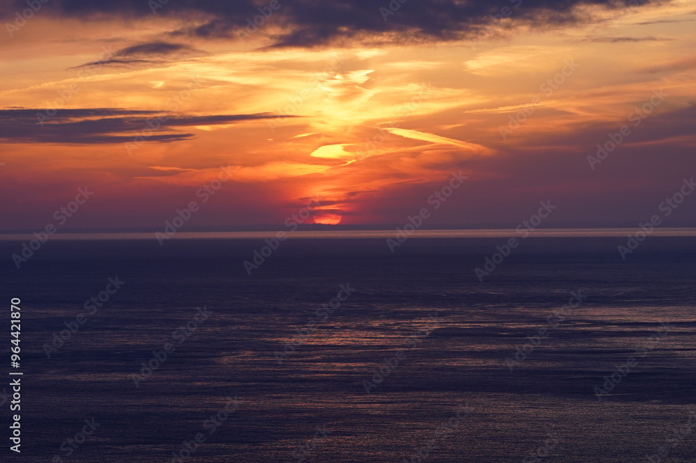 雲のある水平線に沈む夕陽