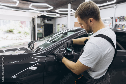 Obraz na płótnie Professional Auto Mechanic Applying Protective Film to Car Mirror in Workshop