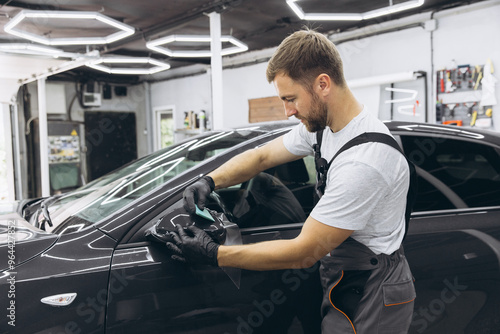 Professional Auto Mechanic Applying Protective Film to Car Mirror in Workshop