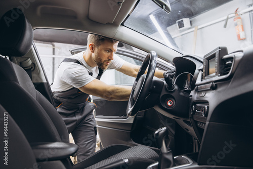 A mechanic's shop worker sitting in a car and checking on steering wheel on a car service. photo