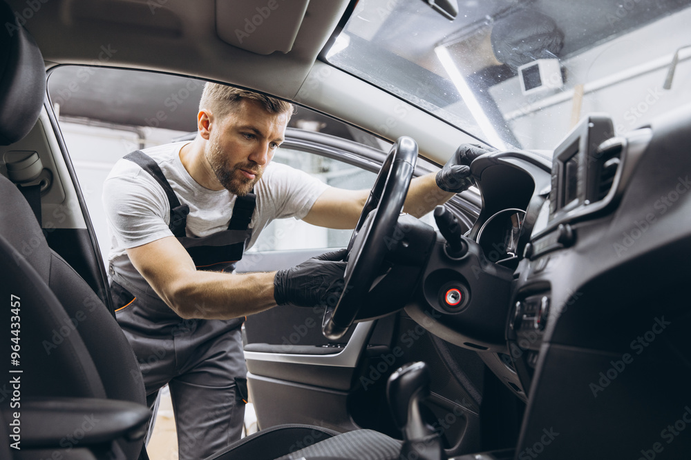A mechanic's shop worker sitting in a car and checking on steering wheel on a car service. A mechanic's shop worker sitting in a car and checking on steering wheel on a car service.