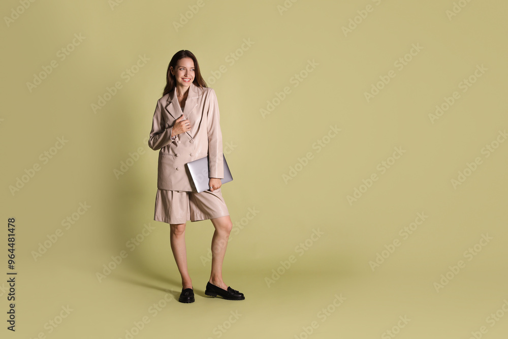 Beautiful woman in stylish beige suit with laptop on olive background, space for text Beautiful woman in stylish beige suit with laptop on olive background, space for text