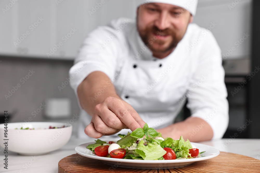 Professional chef decorating delicious salad with basil at table in kitchen, selective focus Professional chef decorating delicious salad with basil at table in kitchen, selective focus