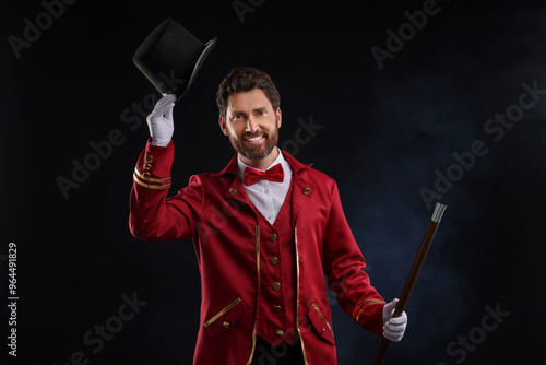 Portrait of showman in red costume and hat on black background