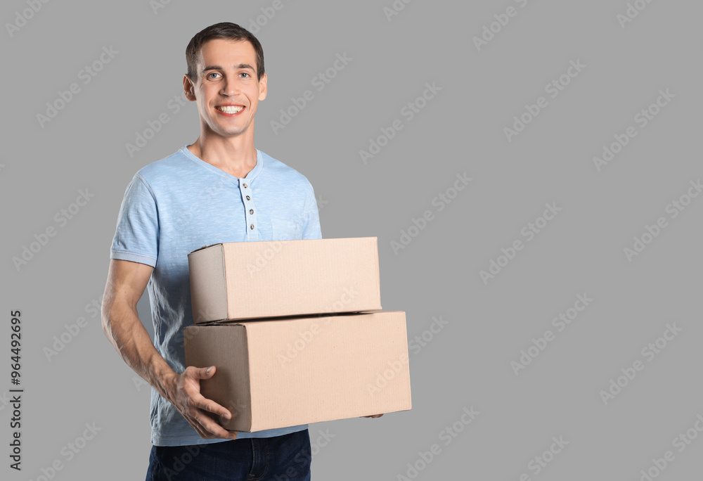 Moving into new house. Man with cardboard boxes on grey background, space for text Moving into new house. Man with cardboard boxes on grey background, space for text