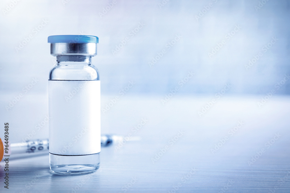 Medication in glass vial with blank label and syringe on white wooden table, space for text Medication in glass vial with blank label and syringe on white wooden table, space for text
