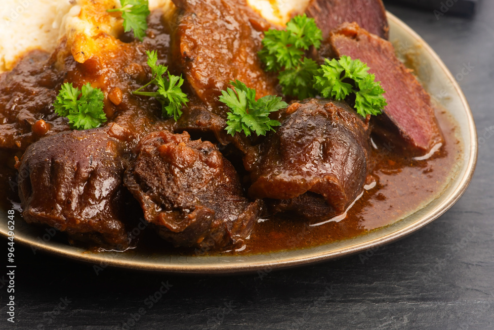 Stewed goose stomach. Traditional Polish meat on a dark background. Stewed goose stomach. Traditional Polish meat on a dark background.
