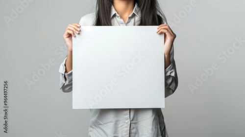 A person holding a blank white canvas against a plain gray background, inviting creativity and endless possibilities for artistic expression. photo