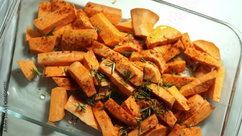 Housewife sprinkling raw sweet potato slices in glass dish. High quality 4k footage
