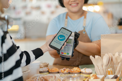 Woman Using Mobile Phone Payment to Transfer Money to bakery Shop Seller.NFC QR code device,payWave,contactless payment code for fast digital transaction,Online banking app on mobile phone,paperless