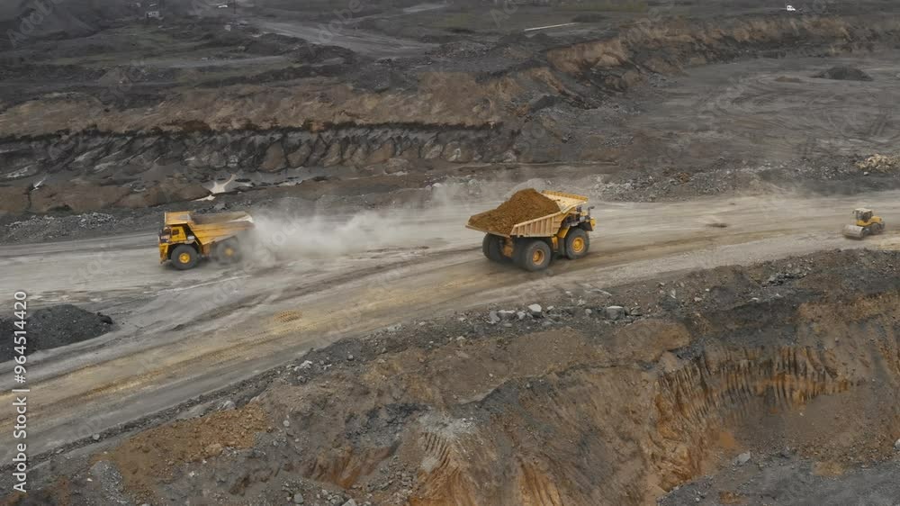 Large quarry dump truck. Loading rock in dumper. Loading coal into truck. Mining car machinery to transport coal. Open pit mine quarrying extractive industry stripping work. Big Yellow Mining Trucks Large quarry dump truck. Loading rock in dumper. Loading coal into truck. Mining car machinery to transport coal. Open pit mine quarrying extractive industry stripping work. Big Yellow Mining Trucks