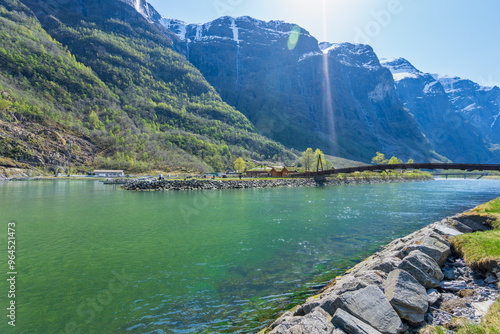 Admire the tranquil views of Sognefjord, with rest stops along the way featuring a small wooden bridge and calm waters surrounded by majestic mountains. Sognefjord, Norway.